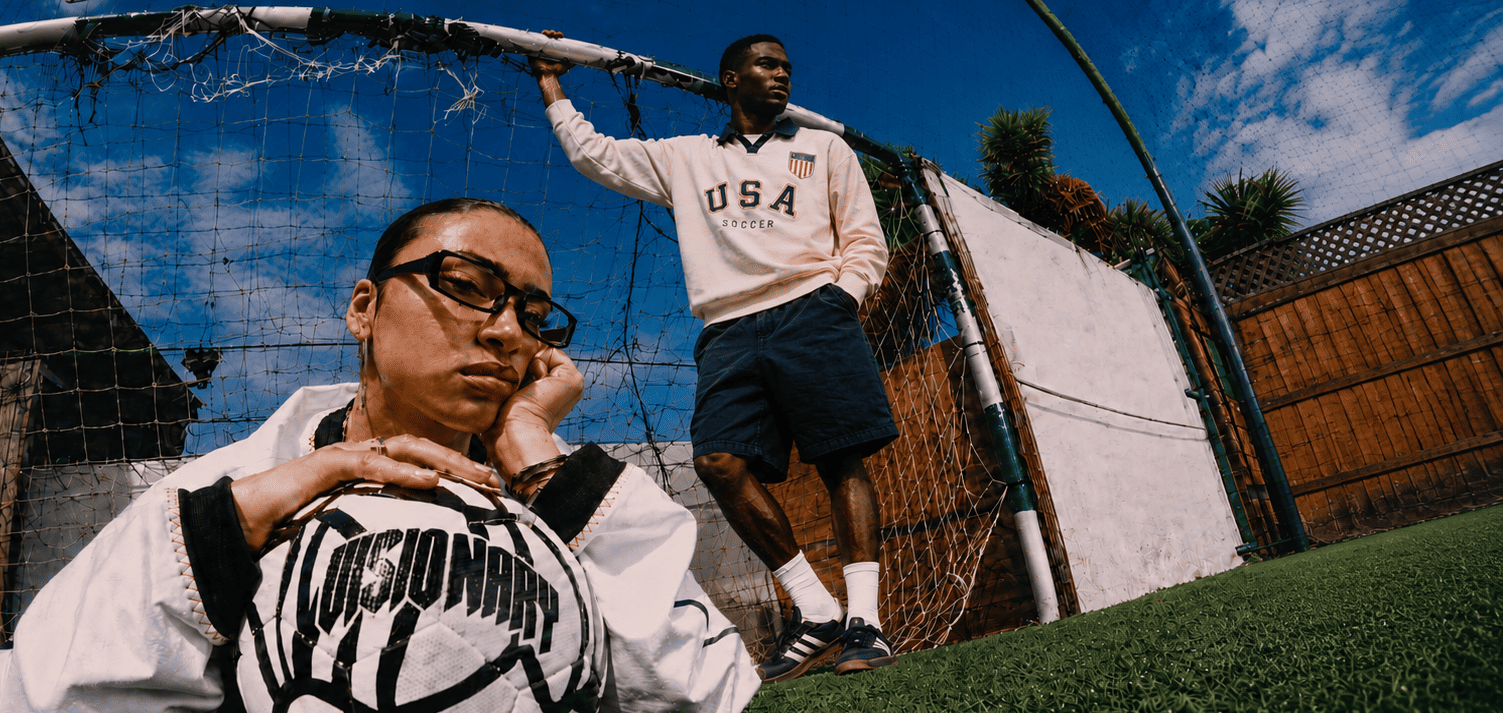 Two people standing on a grassy area with a basketball court in the background.