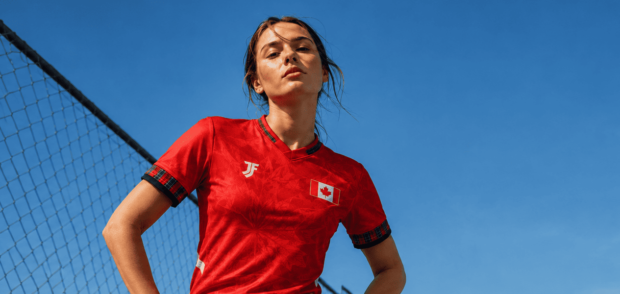 Person wearing a red sports jersey on a sports field with a clear blue sky.