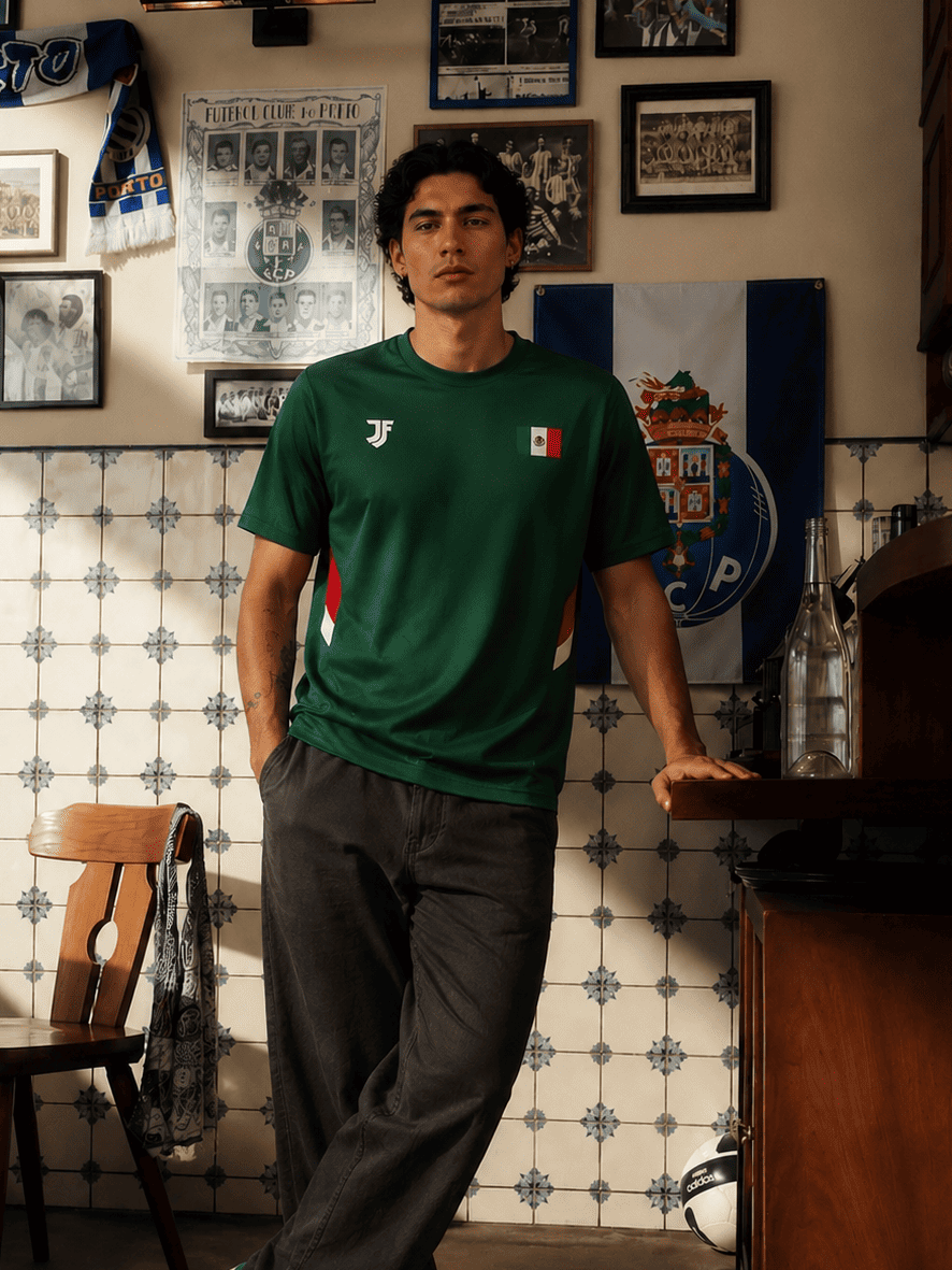 Man wearing a green t-shirt with a logo in a room with tiled walls and framed pictures.